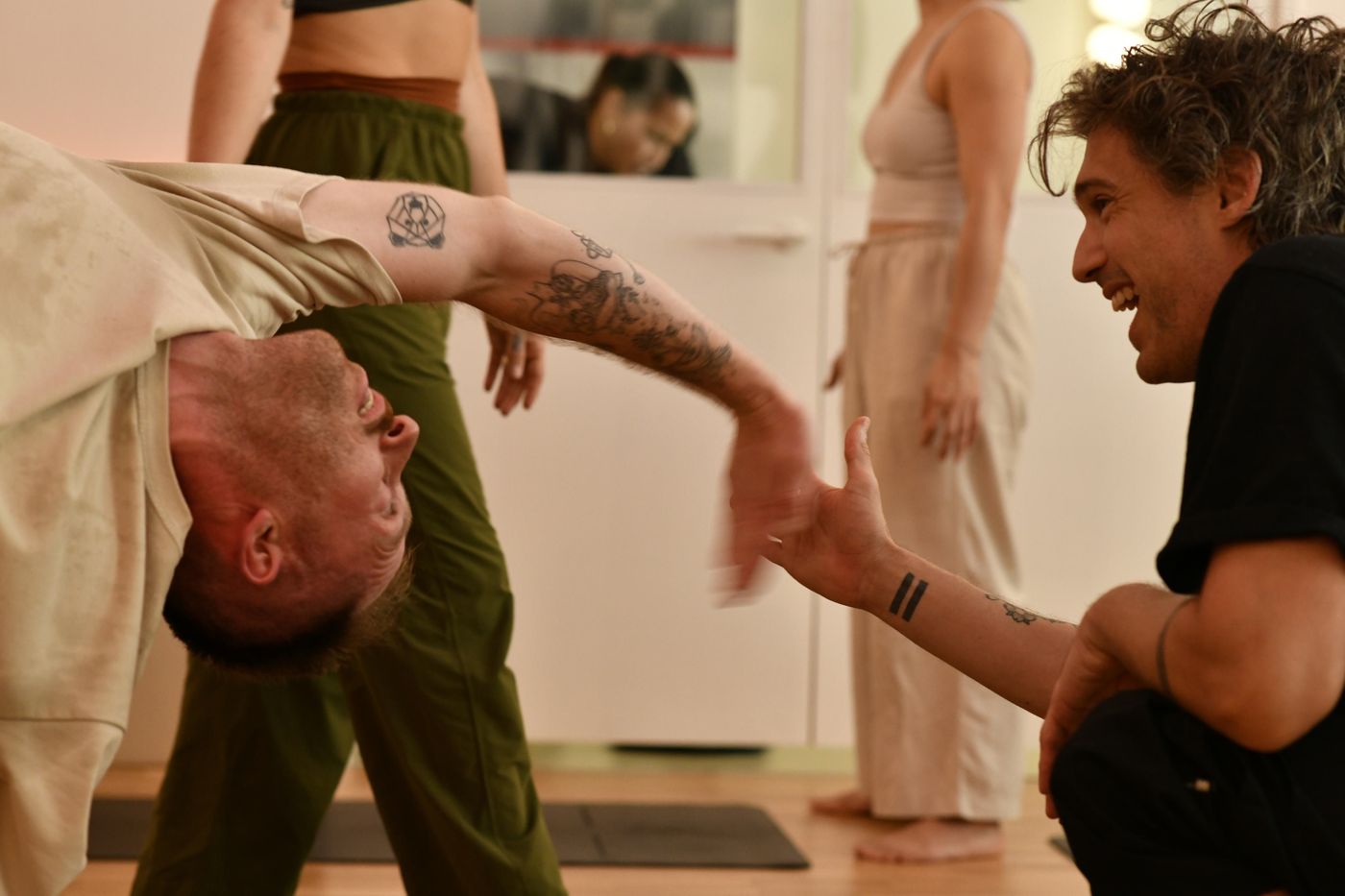 Two people working through a partner movement exercise, laughing, at MVMT Studio